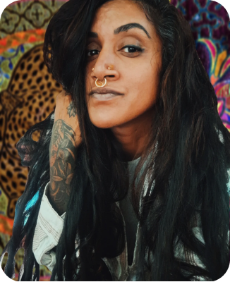 This image shows a person featuring detailed arm tattoos and facial piercings.