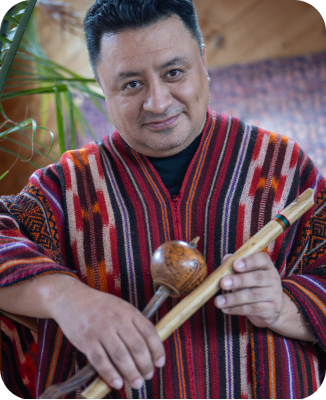 This image features a traditional Andean musician holding a Quena flute and a gourd shaker