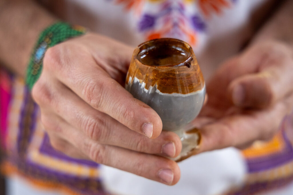 This is a hand-thrown ceramic cup, potentially glazed with iron oxide, designed for holding small beverages.