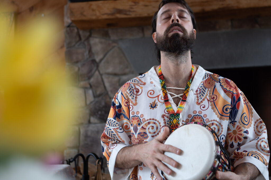 This image shows a person focused on playing a musical instrument, likely during a meditative or spiritual gathering