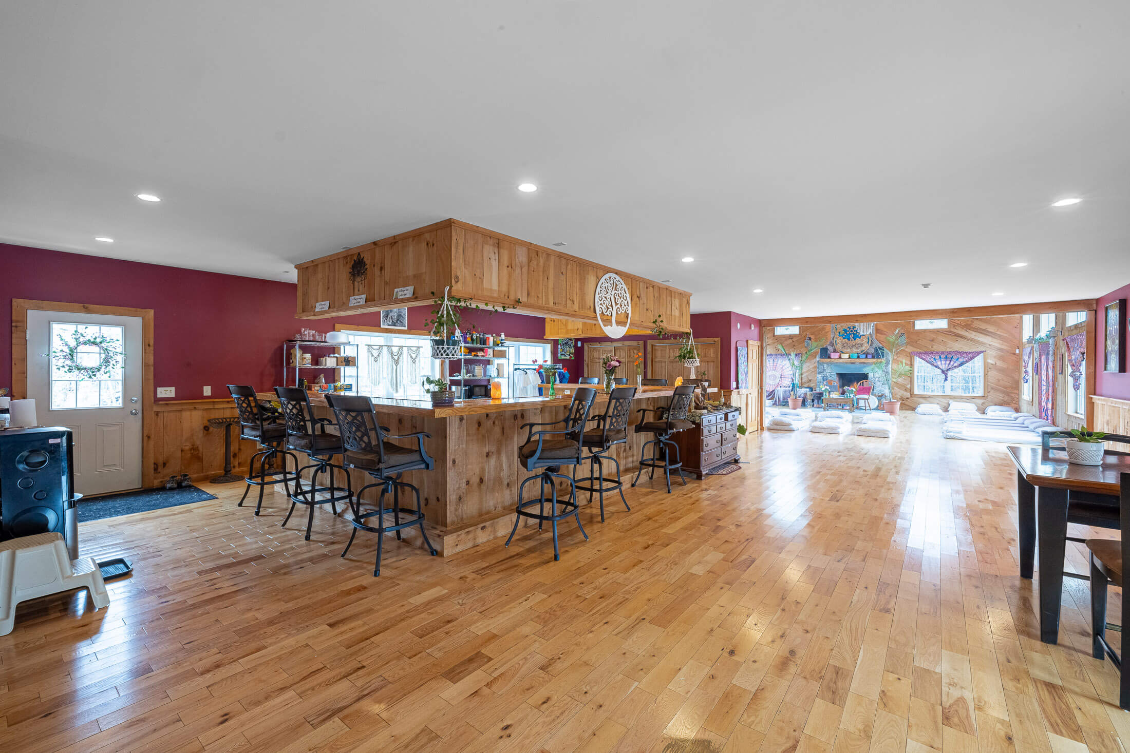 The space features rustic wood paneling, a bar area, and a large open room with cushions for group activities.