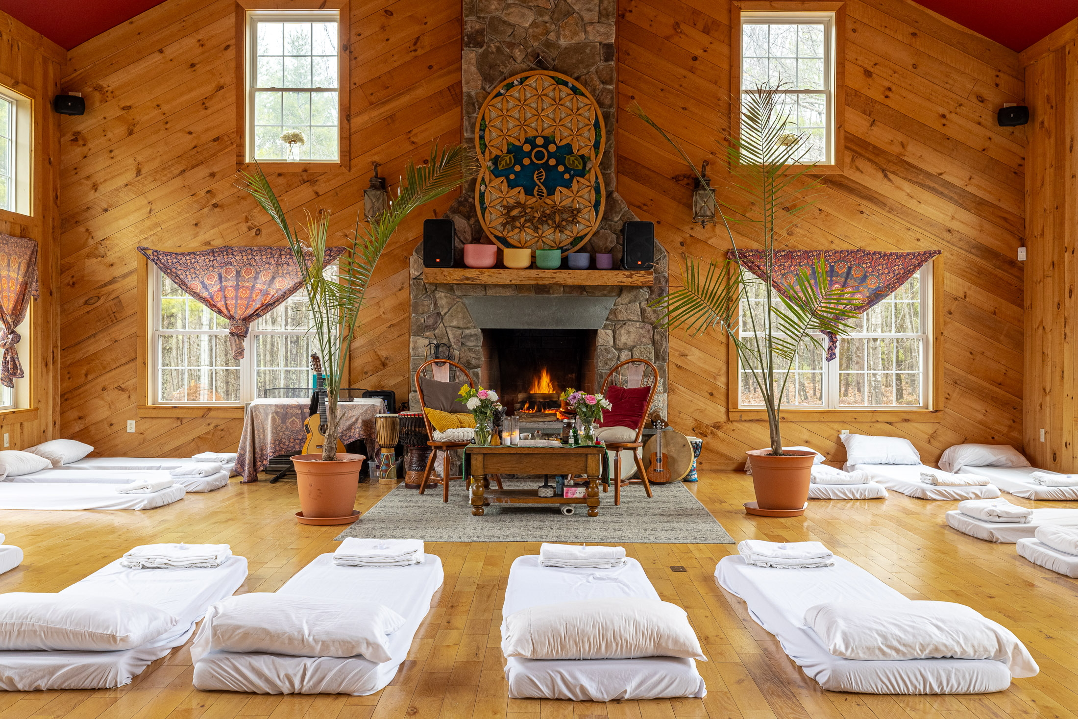 The image shows a spacious, rustic wellness studio or retreat room with natural wood-paneled walls and flooring.